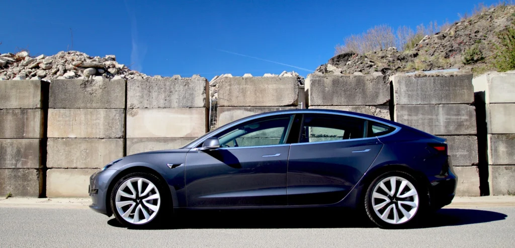 Grijze Tesla Model 3 uit 2020 voor een muur van betonblokken
